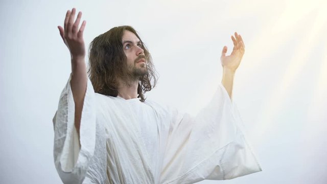 Saint man in robe raising hands to light, praying to God, religious conversion