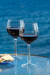 Aperitif, red wine in glasses served with cheese on outdoor tessace witn sea view