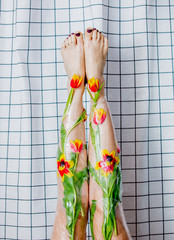 woman holds her legs up wrapped with cellophane and flowers.
