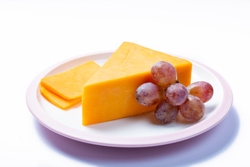 Piece of hard orange Cheddar cheese on white board isolated close up