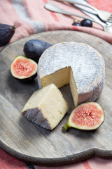 Round mature French Tomme cheese with cutted piece close up