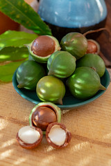 New harvest of ripe fresh Australian macadamia nuts in shell with leaves