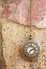 Vintage golden pocket watch on rock background, time concept.