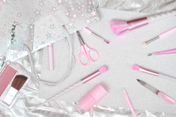 Feminine accessories and unicorn makeup brushes and nail polish manicure tools on silver pink background. Flat lay with copy space, beauty and cosmetics blogger concept