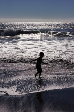 Boy runs in the surf of the waves of Pasific ocean