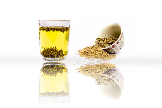 Herbal detoxifying drink isolated on white i.e. Jeera water with some raw organic cumin in a glass bowl.