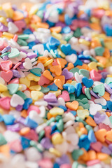 Fototapeta na wymiar Happy Valentine day. Pile of small colorful purple, pink, orange, yellow, white, green and blue candies hearts of different colors. Concept of love and February holiday. Selective focus in the middle