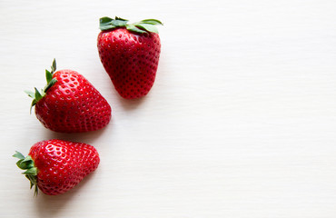Fresh strawberries on the white wooden background, copy space. Sweet, juicy, ripe strawberries. Harvest of organic local red, large strawberries. Delicious and healthy food. Vitamin-rich food.  