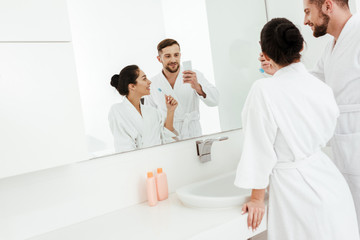 selective focus of cheerful man taking photo with happy woman holding toothbrush