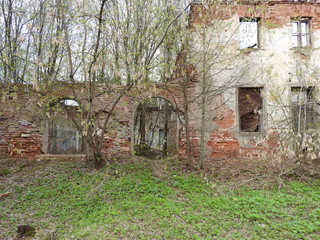 Fototapeta na wymiar Ruins of an old old red brick and plaster building in the spring in the village of Grebnevo near Moscow, Russia.