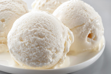 Fototapeta na wymiar ice cream scoops on white plate macro against neutral background