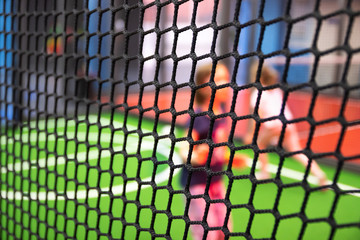 Blurred children are playing behind the net at indoor playground in activity park.