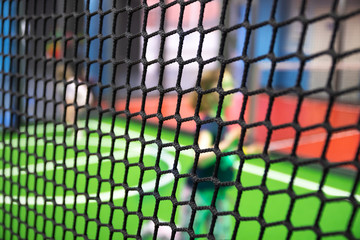 Blurred children are playing behind the net at indoor playground in activity park.