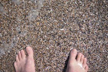 feet on the sand in the sea in summer