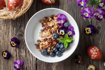 Obraz na płótnie Canvas Breakfast cereals with yogurt, blueberries and flowers
