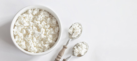 fresh cottage cheese in white porcelain Cup on white background top view. cottage cheese for Breakfast in a bowl and spoons. copy space. flat lay.