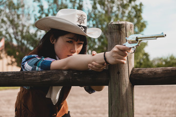 Portrait of a beautiful Chinese female cowgirl shooting with a weapon