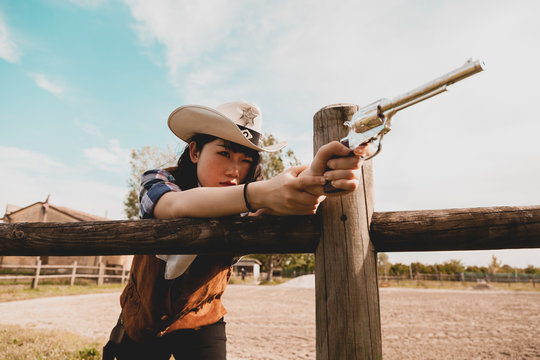 Portrait of a beautiful Chinese female cowgirl shooting with a weapon