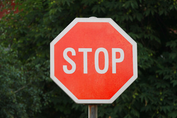 Stop sing with green tree in background