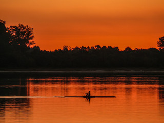 deportista remando en el r&iacute;o en un rojizo atardecer