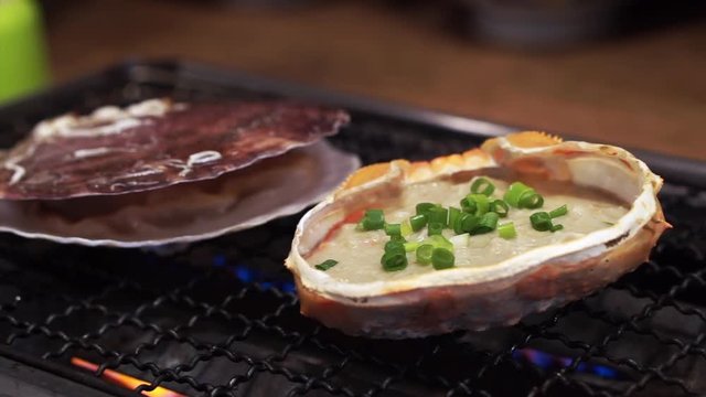 Japanese kani miso in crab shell and scallop on grill in restaurant