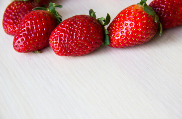 Fresh strawberries on the white wooden background, copy space. Sweet, juicy, ripe strawberries. Harvest of organic local red, large strawberries. Delicious and healthy food. Vitamin-rich food.