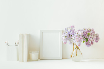 Home interior with decor elements. White frame, branches of lilac in a vase, interior decoration