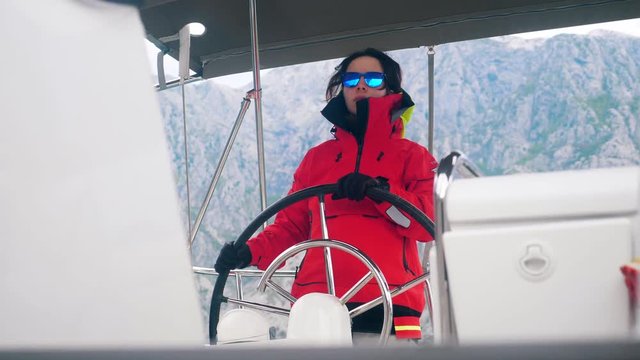 A woman wearing an anorak is navigating a yacht