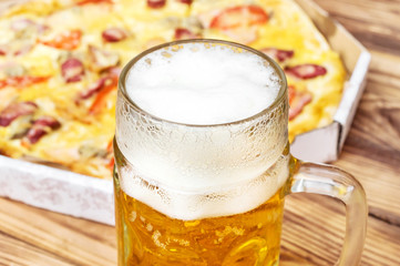 Glass of beer on the table with tasty pizza. Close up.