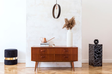 Stylish and eclectic interior of living room with design retro cabinet, round pendant lamp, marble pedestals and elegant accessories. Abstract background wall. Minimalistic home decor. Copy space. 