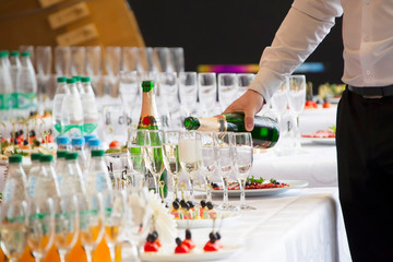 Waiter's hands pouring a drink into glasses