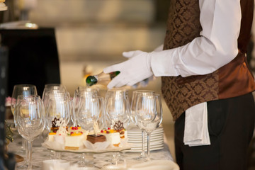 Waiter's hands pouring a drink into glasses