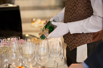 Waiter's hands pouring a drink into glasses