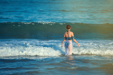 Fototapeta premium Beautiful young woman walking in the ocean with waves. Indian deep ocean