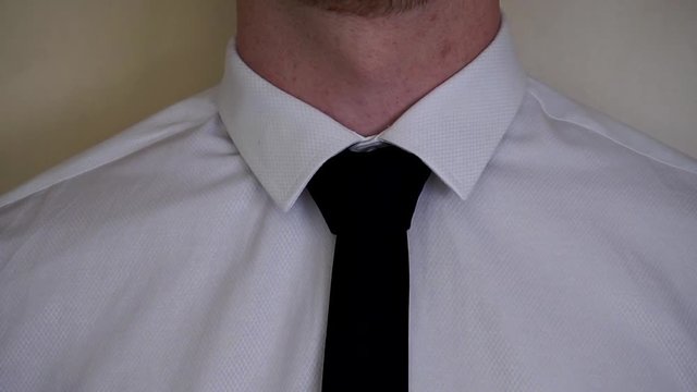 Young caucasian man fixing black tie wearing white shirt