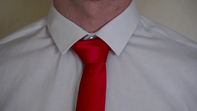 Young caucasian man fixing red tie wearing white shirt