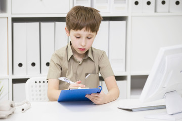 Junior school student does his homework. A boy with a pen in his hands writes something. A child solves a problem