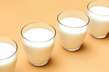Glasses of milk on orange background