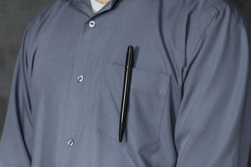 man in grey shirt with pen in pocket