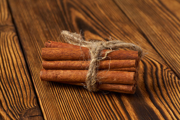 A bunch of cinnamon tied with a rope on a wooden background.