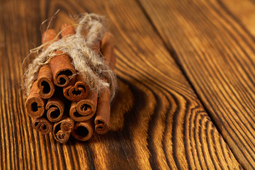 A bunch of cinnamon tied with a rope on a wooden background.