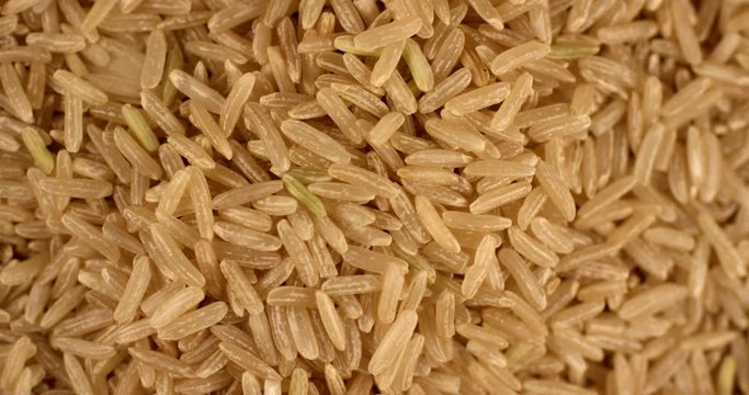 Paddy grain unpolished brown rice falling and rotating in slow motion. Extreme close up top view, shot on RED 6K camera