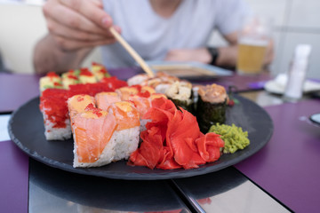 Sushi closeup. The guy eats sushi and rolls with chopsticks