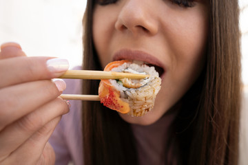 Sushi and mouth girl closeup. The girl eats sushi and rolls with chopsticks