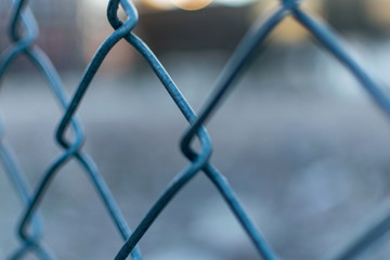 Closeup of a metal mesh fence with blurred out bokeh background