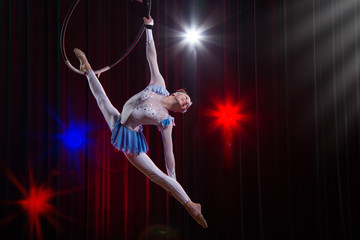 Fototapeta na wymiar Performs a circus girl actress. Circus aerial gymnast on the hoop. Acrobatics. Teenager performs an acrobatic trick in the air