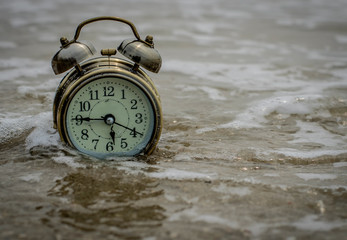 Old Alarm clock put on sand with web from sea.