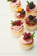 selective focus of cupcakes with cream and berries on white surface