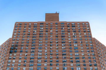 Tall apartment building complex in Harlem, with visible fire damage on the left side, New York...