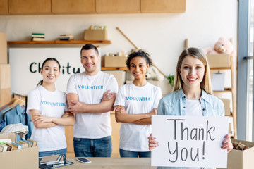 selective focus of pretty girl holding placard with thank you text while standing near...